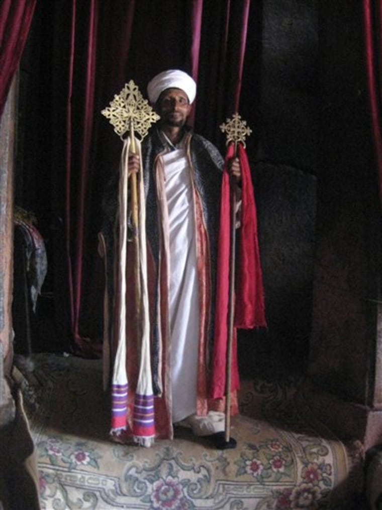 This April 2010 photo shows a priest inside a church at Lalibela, Ethiopia. Lalibela has a winding complex of 11 churches cut out of the rust-red granite tucked into a wind-swept moonscape. Legend claims it's the work of angels, but in reality the complex was commissioned by the powerful 12th Century King Lalibela and picked out of the rock with hammers and chisels over decades. 